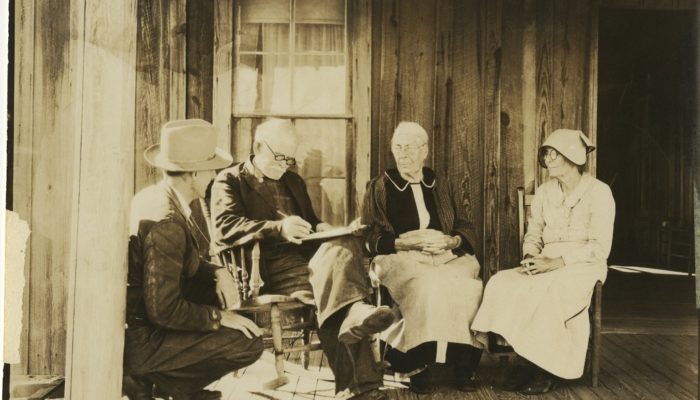 4 people on the porch of old home