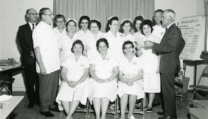 group of women in white uniforms with company men